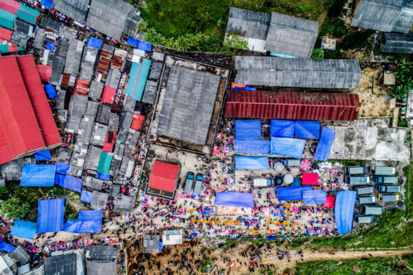 Aerial view of a crowded outdoor market with colorful tarps over stalls and narrow walkways.