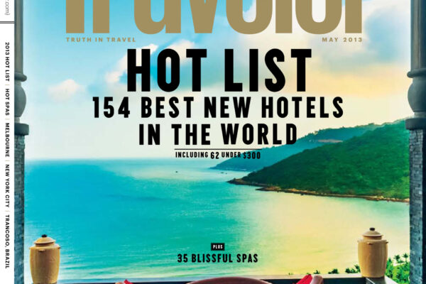 Cover of Condé Nast Traveler magazine featuring a sea view from a deck, with a red curved chair in the foreground and bold 'Traveler' typography across the center of the image.