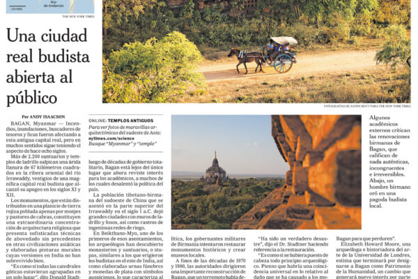 Photo of ancient Buddhist temple ruins with a carved brick façade and a blue cart pulled by horses on a dirt road nearby.