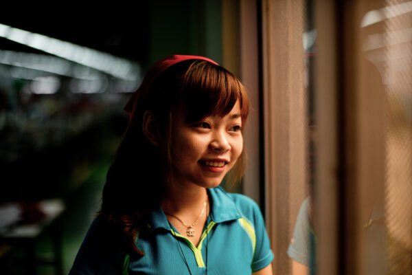 Young woman with a red headband smiling as she looks out a train window at night.