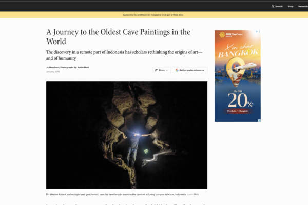 Cave explorer with headlamp climbs through a dark, rocky cave interior under spotlighted walls