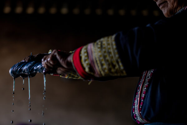 Person in traditional embroidered clothing washing their hands, water droplets falling from their cupped hands.